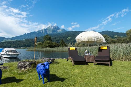a sheep standing in the grass next to chairs and an umbrella at Seehotel Sternen in Luzern