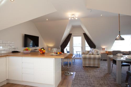 a kitchen and living room with white cabinets at Lochiel Villa Guest House in Fort William