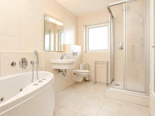 La salle de bains est pourvue d'une baignoire, d'un lavabo et de toilettes. dans l'établissement Two-Bedroom Holiday home in Großenbrode 11, à Großenbrode