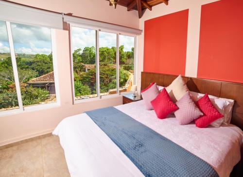 a bedroom with a bed with red walls and windows at Hotel Mansión Barichara in Barichara