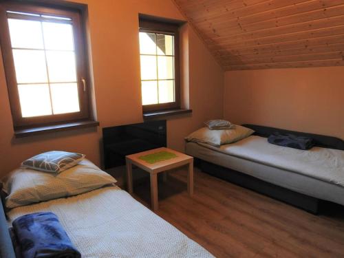 a room with two beds and a table and two windows at Przestronny Dom w gorach w sercu Karkonoszy in Przesieka