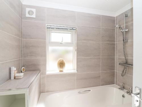 a bathroom with a bath tub and a window at 12 Bucklesham Park in Ipswich