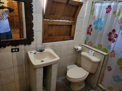 La salle de bains est pourvue de toilettes, d'un lavabo et d'un miroir. dans l'établissement Hostal casa de las gargolas, à Amapala