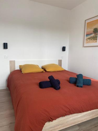 1 cama grande con almohadas amarillas y manta roja en La Brise Marine, calme, Océan, 350m plage, en Loctudy
