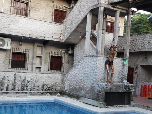 a man standing on a pole next to a swimming pool at Hostal casa de las gargolas in Amapala