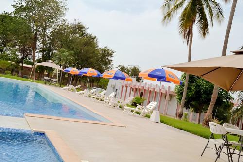 a swimming pool with umbrellas and lounge chairs and a pool at Hôtel Printemps Mont Korhogo in Korhogo