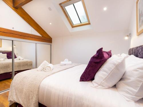 um quarto com uma grande cama branca com almofadas roxas em Willow Tree Barn em Kendal