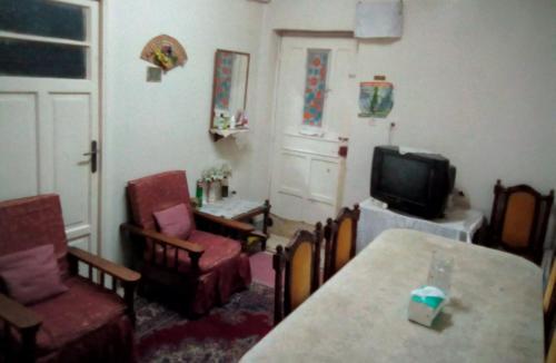 a living room with a tv and a table and chairs at غرفة خاصة فى رشيد 