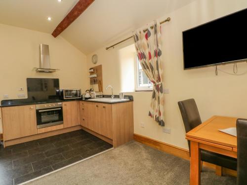 a kitchen with a table and a tv on the wall at Swallows Nest in Macclesfield