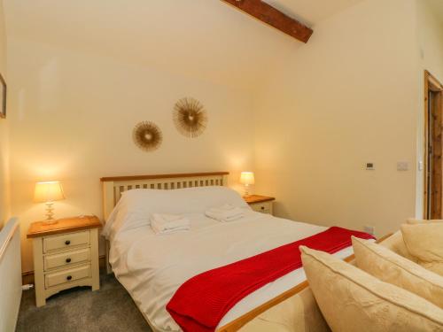 a bedroom with a bed with a red blanket on it at Swallows Nest in Macclesfield