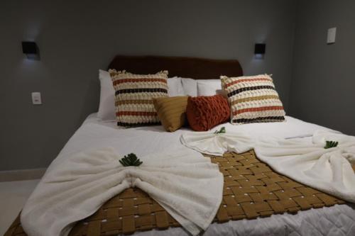 a bed with white blankets and pillows on it at Villa Xodó in Fernando de Noronha