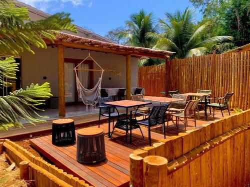 a wooden deck with tables and chairs and a fence at Villa Xodó in Fernando de Noronha