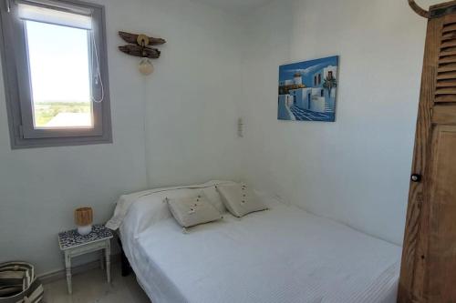 une chambre blanche avec un lit et une fenêtre dans l'établissement Appartement vue mer climatisé Seaview AC apartment Saint Pierre la Mer, à Fleury