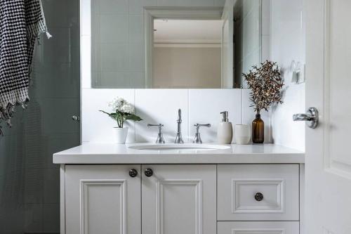 a white bathroom with a sink and a mirror at Nest on the Hill - A Luxurious Escape in Red Hill South