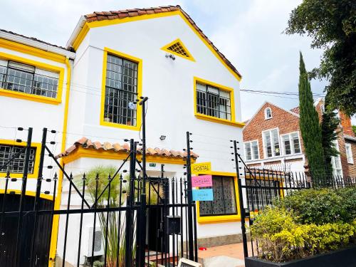 una casa blanca y amarilla con una valla negra en Hostal Macondo Bogotá en Bogotá