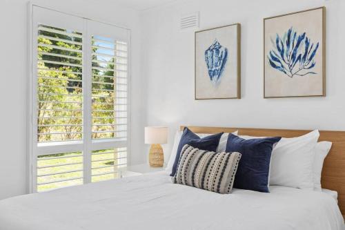 een slaapkamer met een bed met blauwe en witte kussens bij Swell@Blairgowrie - Sleeps nine! in Rye
