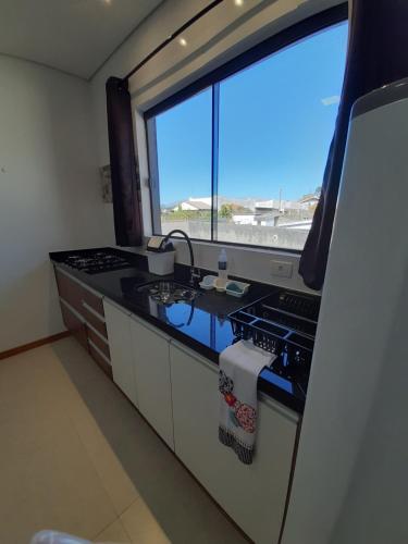 a kitchen with a stove and a large window at Alpes Flats in Campos do Jordão