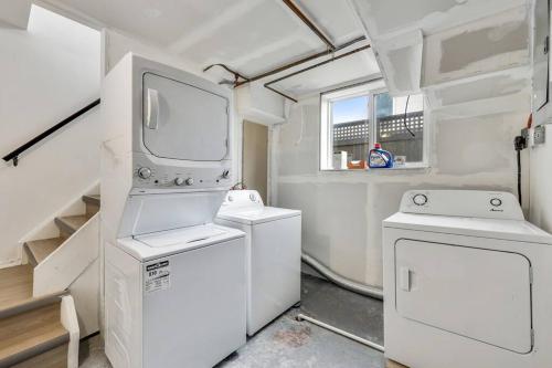 a laundry room with two machines and a tv at Roxboro #1 Premium Central 3BR Home Parking, Wifi in Calgary