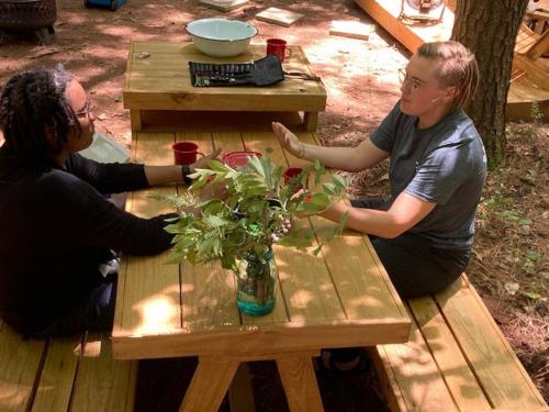 two people sitting at a picnic table with a vase of flowers at Tentrr Signature Site - Herb'n Soul Sanctuary in Stone Mountain