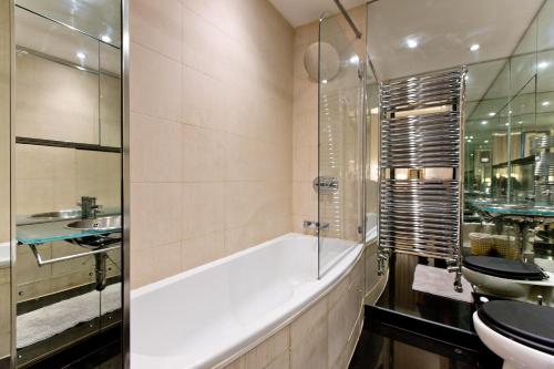 a bathroom with a tub and a toilet and a sink at Harrods Hideaway 3 Bedroom Flat in London