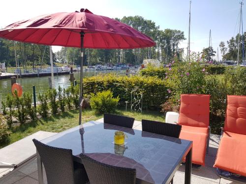ein Tisch mit einem roten Sonnenschirm auf einer Terrasse in der Unterkunft Kapitänsresidenz - Haus direkt am Wasser in Ückeritz