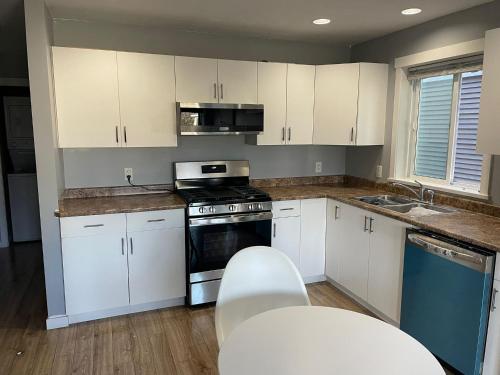 a kitchen with white cabinets and a stove and a sink at Sooke Vacation suite in Sooke