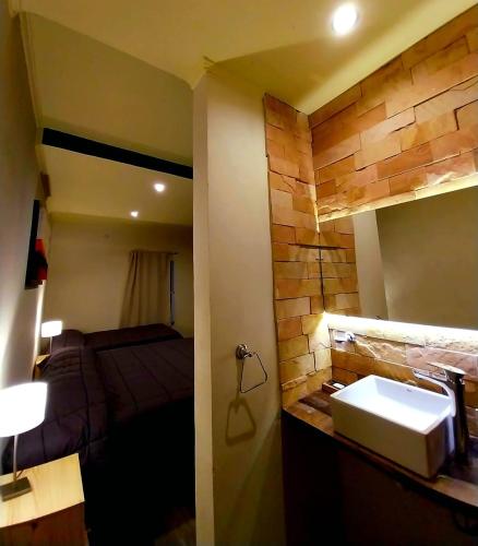 a bathroom with a sink and a bed in a room at Hostería Jasy in Colonia Carlos Pellegrini