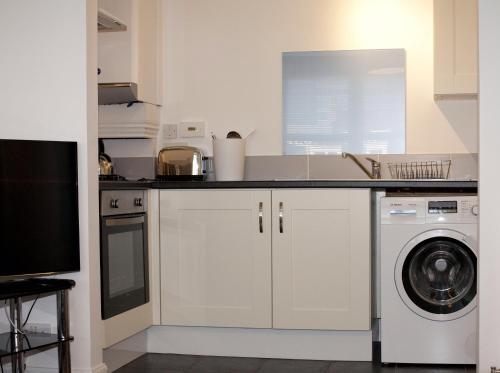 a kitchen with a sink and a washing machine at Aberdeen Serviced Apartments: Charlotte street in Aberdeen