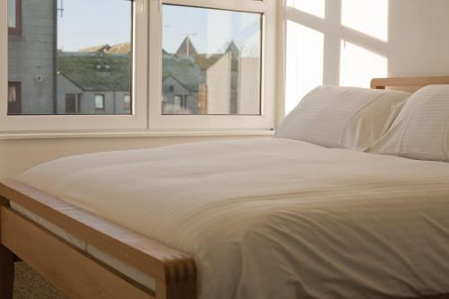 a bed sitting in a room with a window at Aberdeen Serviced Apartments: Charlotte street in Aberdeen