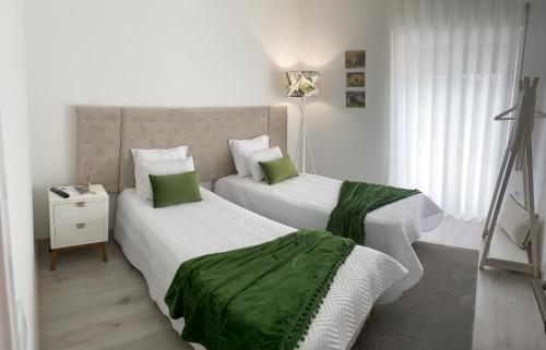 1 Schlafzimmer mit 2 Betten und grüner und weißer Bettwäsche in der Unterkunft ArouceHostel in Lousã