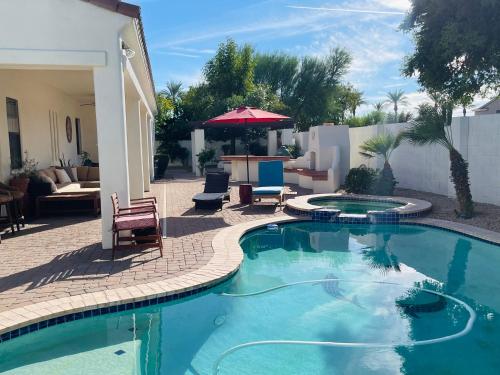 a swimming pool in a yard with chairs and an umbrella at Beautiful Private Casita/Guesthouse w/ Kitchen, Access to Pool/Spa in Goodyear