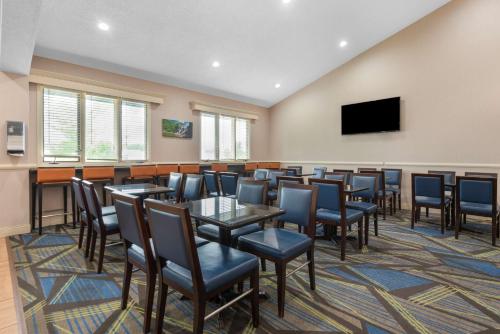 a dining room with tables and chairs and a flat screen tv at Best Western University Inn in Ithaca