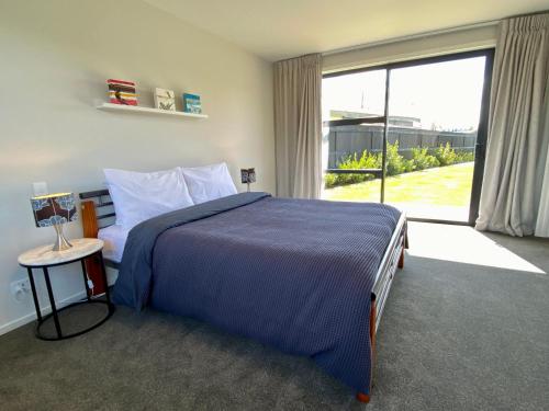 um quarto com uma cama grande e uma janela grande em Stylish, Tasteful in Totara em Twizel