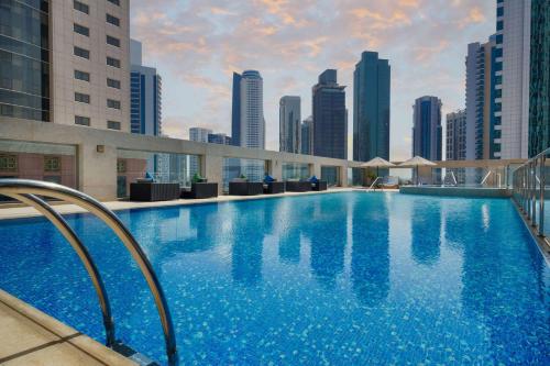uma grande piscina com um horizonte da cidade ao fundo em Wyndham Grand Doha West Bay Beach em Doha