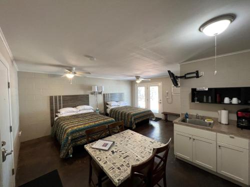 a room with two beds and a table and a kitchen at Painted Sky Inn in Burnet