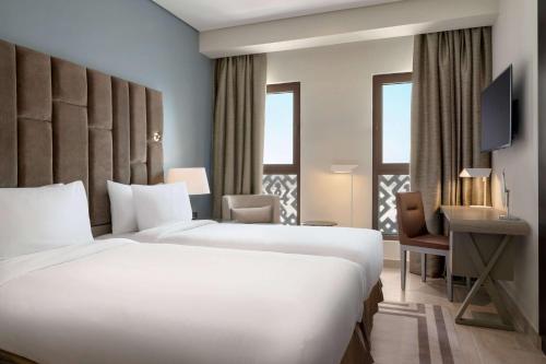 a hotel room with two beds and a desk at Wyndham Residences The Palm in Dubai