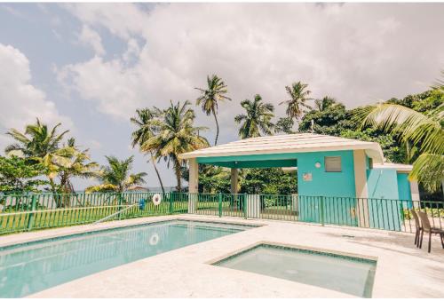 una piscina con una casa azul y palmeras en Casa Del Mar !!! Ocean front villa en Aguada