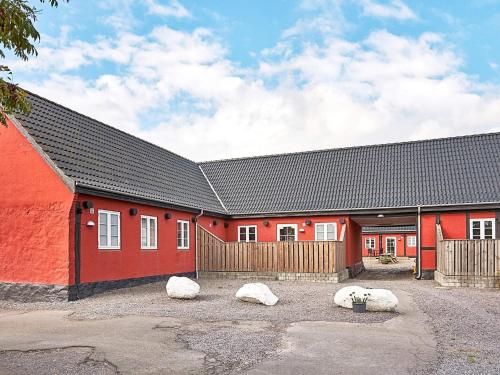 Um edifício vermelho com três pedras à frente. em 5 person holiday home in Aakirkeby em Åkirkeby