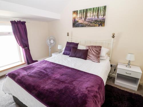 a bedroom with a large bed with a purple blanket at Swn Y Mor in Caernarfon