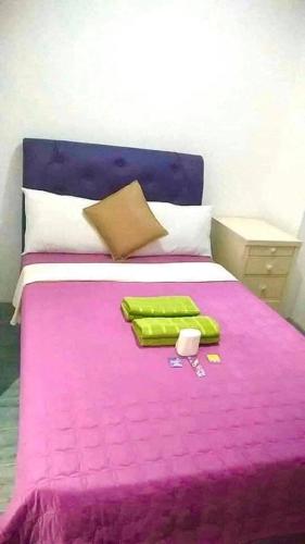 a bedroom with a pink bed with a purple blanket at 25th RESIDENCES- LACSON BACOLOD in Bacolod