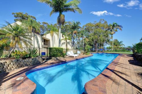 a swimming pool in front of a house with palm trees at The Moorings 23 4 Cromarty Rd air con pool and waterfront in Soldiers Point