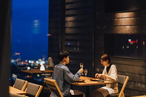 a man and woman sitting at a table with wine glasses at SEKIYA RESORT Galleria Midobaru in Beppu