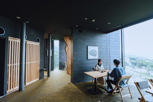 two people sitting at a table in a room with a window at SEKIYA RESORT Galleria Midobaru in Beppu