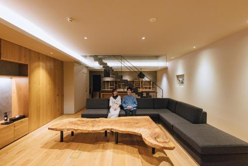 two people sitting on a couch in a living room at SEKIYA RESORT Galleria Midobaru in Beppu
