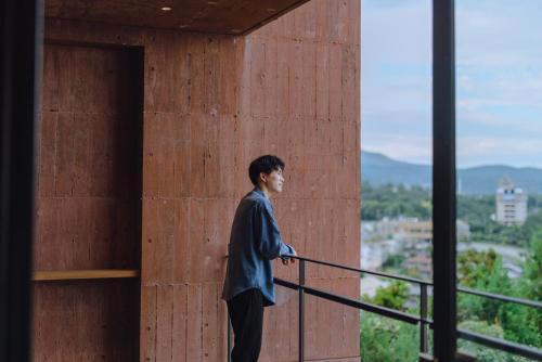 a man standing on the balcony of a building at SEKIYA RESORT Galleria Midobaru in Beppu