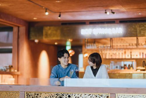a man and a woman sitting at a counter in a restaurant at SEKIYA RESORT Galleria Midobaru in Beppu