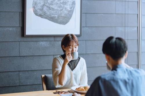 a woman sitting at a table with a cup of coffee at SEKIYA RESORT Galleria Midobaru in Beppu