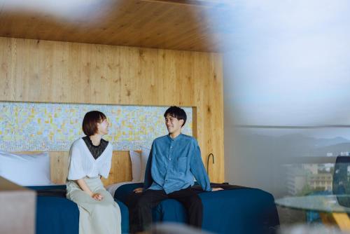 a man and a woman sitting on beds at SEKIYA RESORT Galleria Midobaru in Beppu