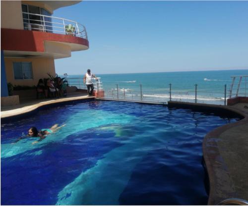 a person in a swimming pool next to a beach at Hotel Arco Iris in Atacames