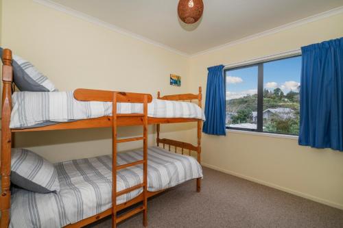 a bedroom with two bunk beds and a window at Hosts on the Coast Laze Away on Cook in Cooks Beach